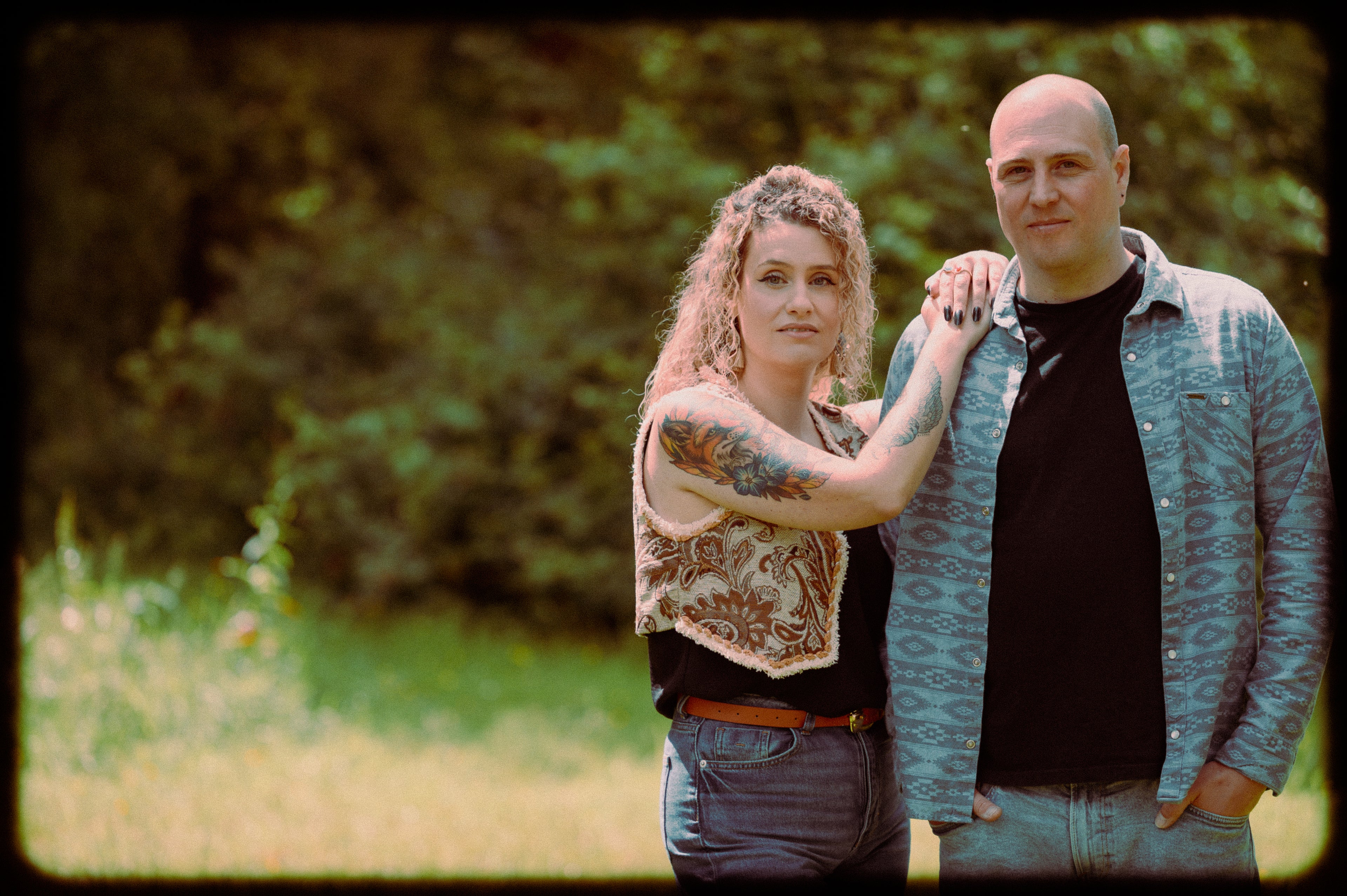 Two people standing outdoors with a blurred natural background